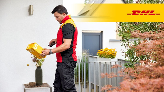Paketbote von DHL scannt Paket vor Haustür